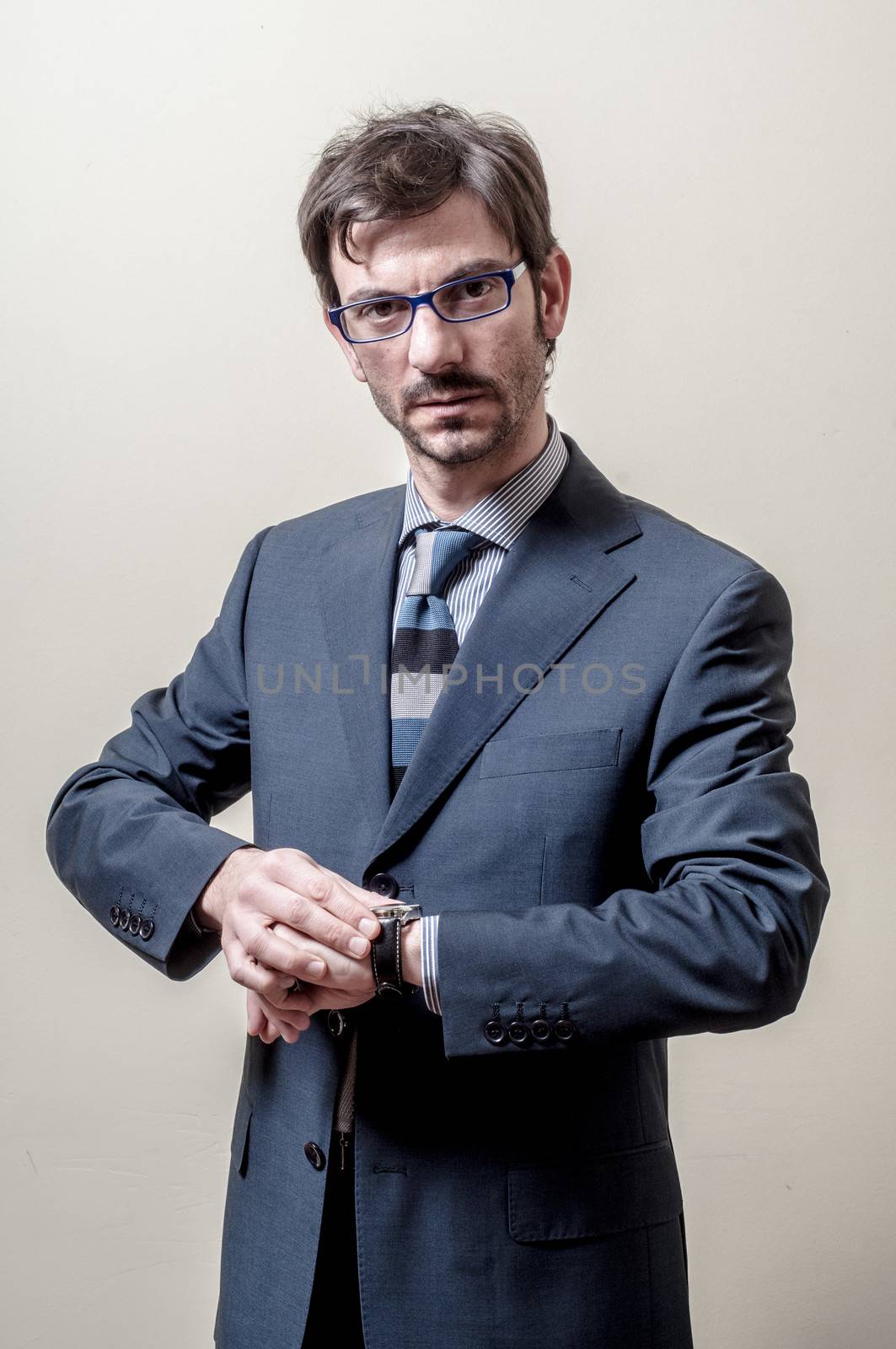 businessman looking wristwatch on gray background