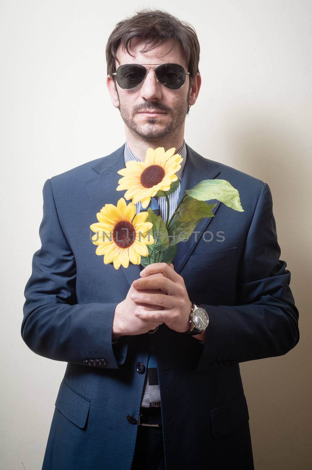 elegant man with daisies on gray background
