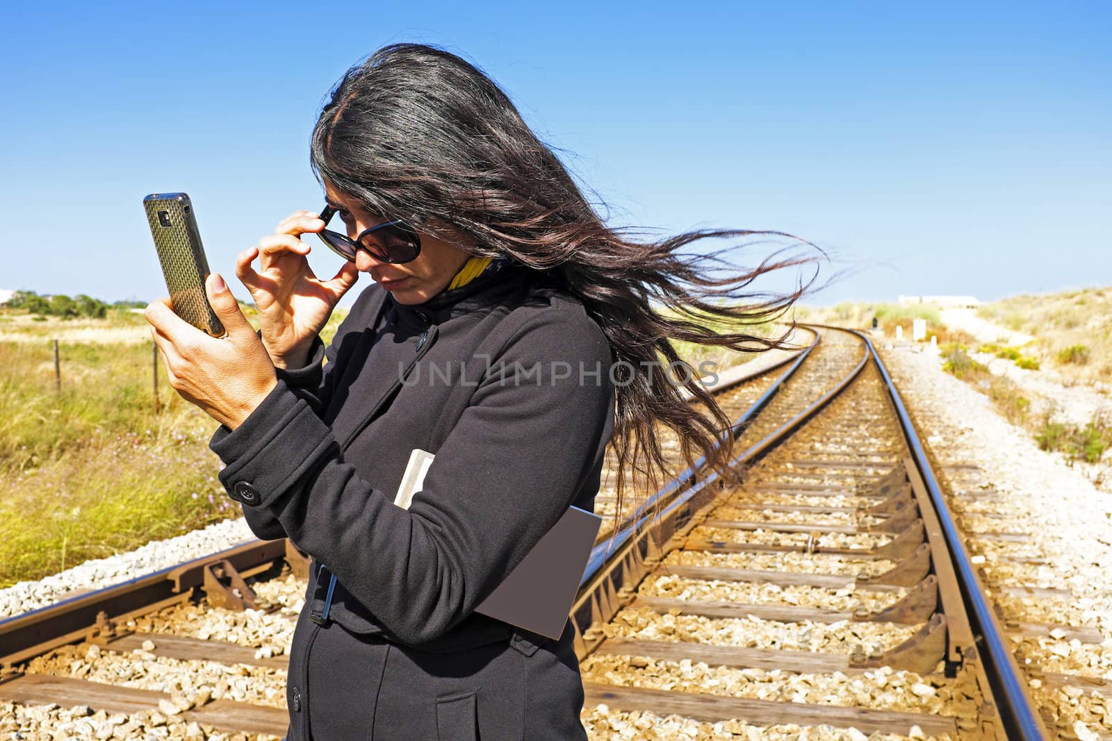 Young beautiful woman rckeading an sms on a railroad track