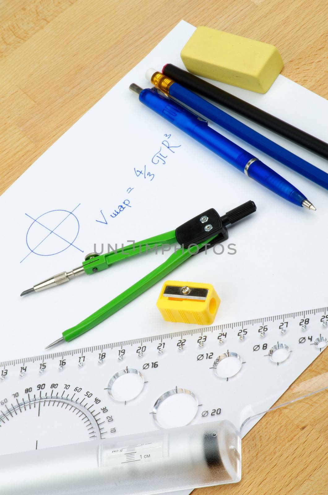 Arrangement School Supplies with Writing Geometrical Formula on White Paper  on Wooden School Desk 