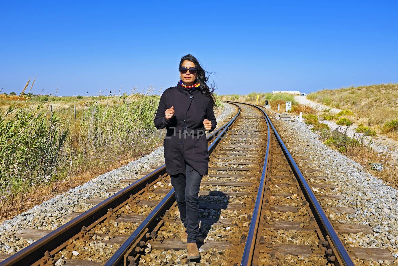 Young beautiful woman running on a railroad track by devy
