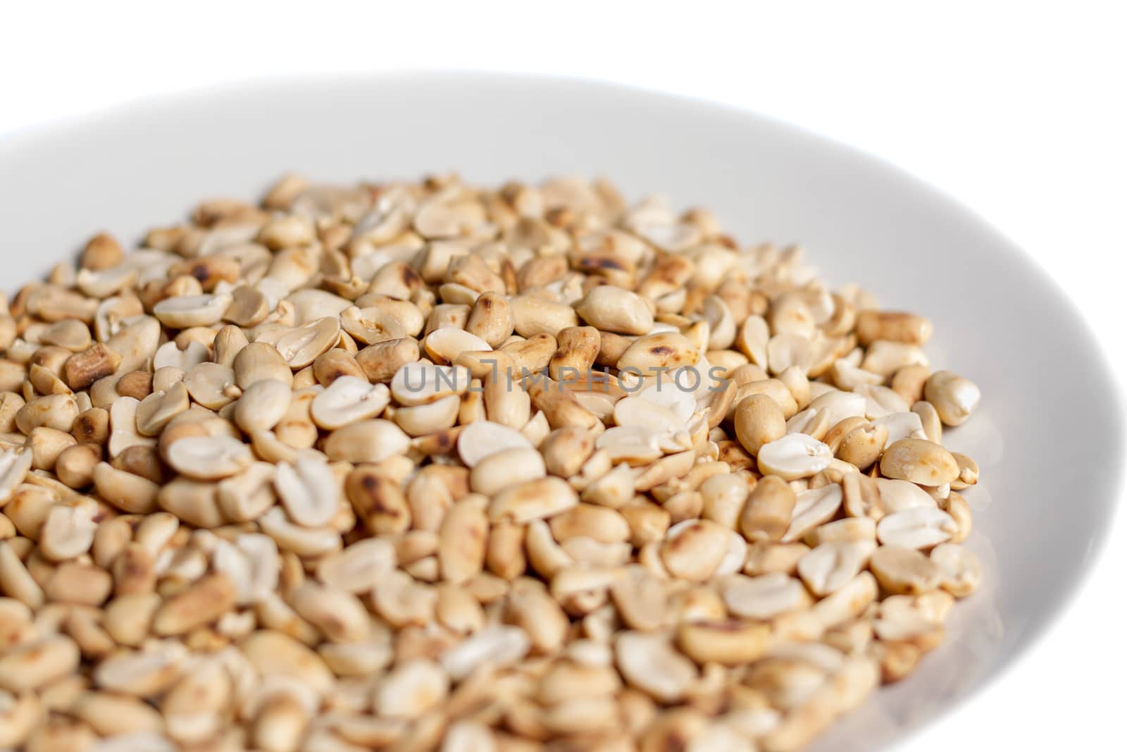 pile of roasted peanuts in a plate on white background