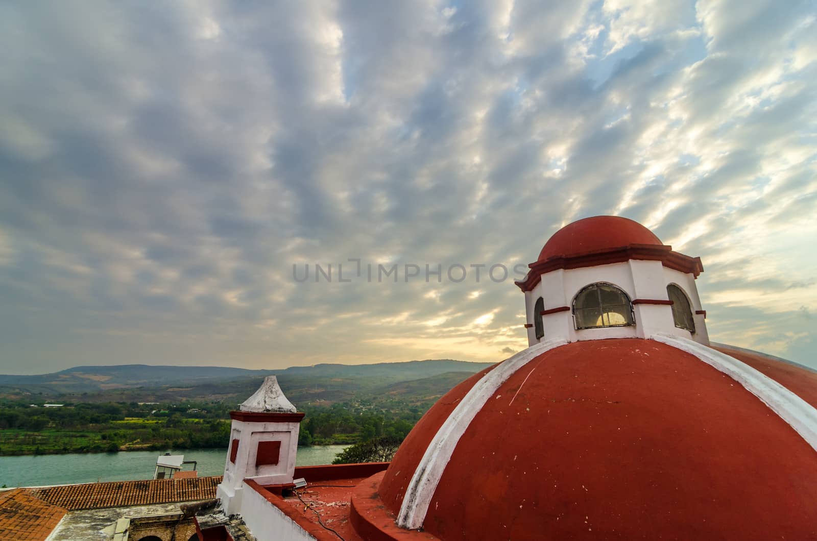 Red dome of a church in Mexico with a dramatic sky