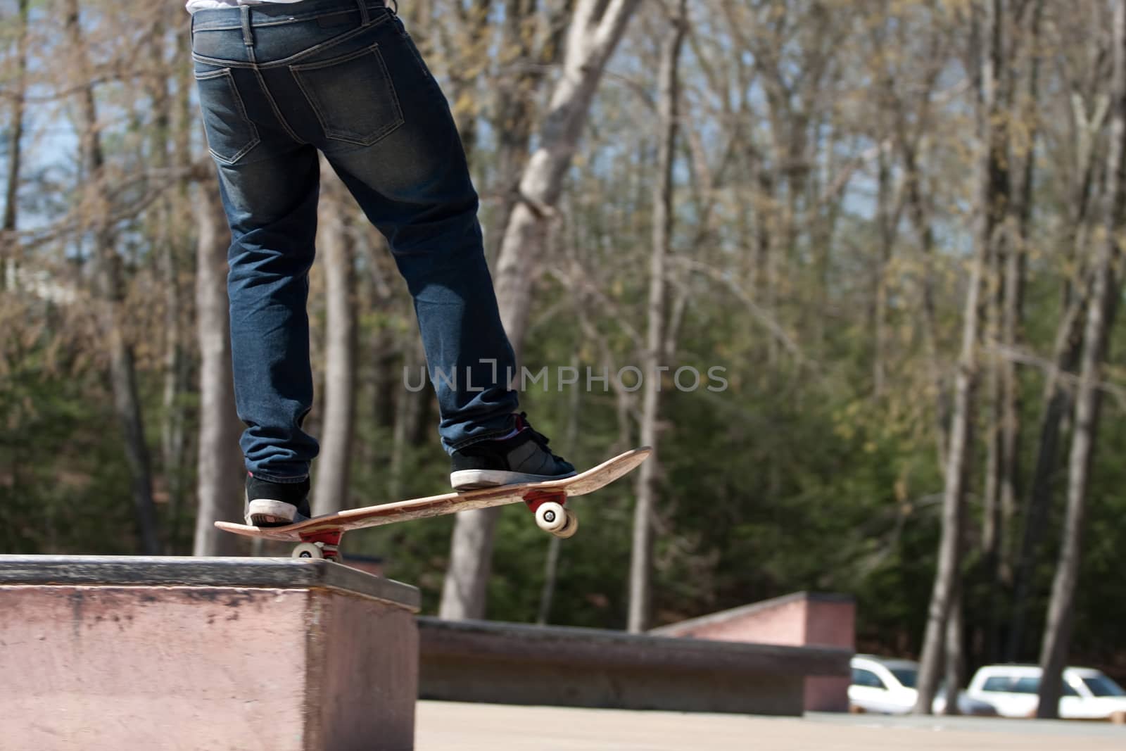 Action shot of a skateboarder skating at the park on a concrete rail.