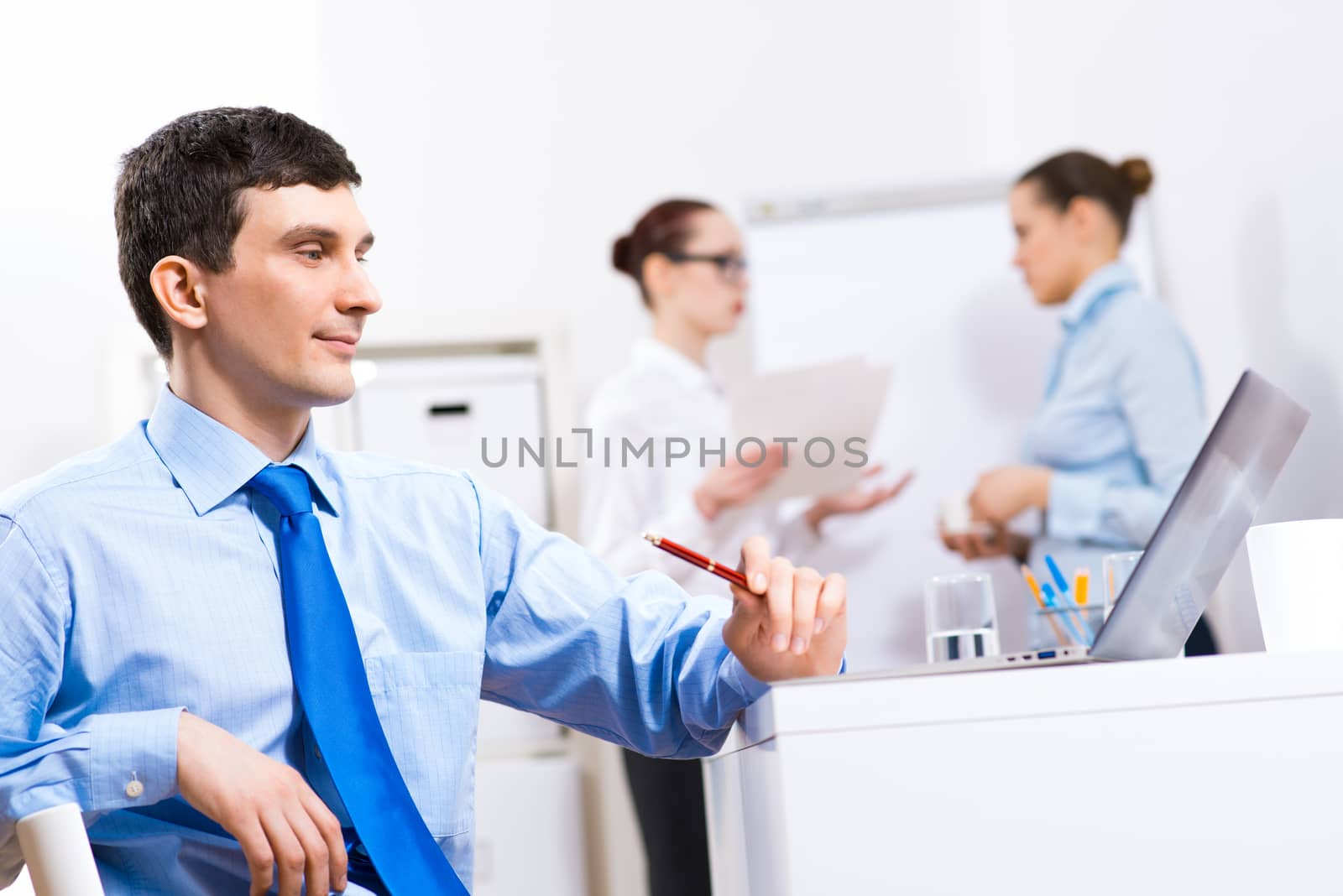 Portrait of a businessman in a blue shirt in the background of colleagues discussing