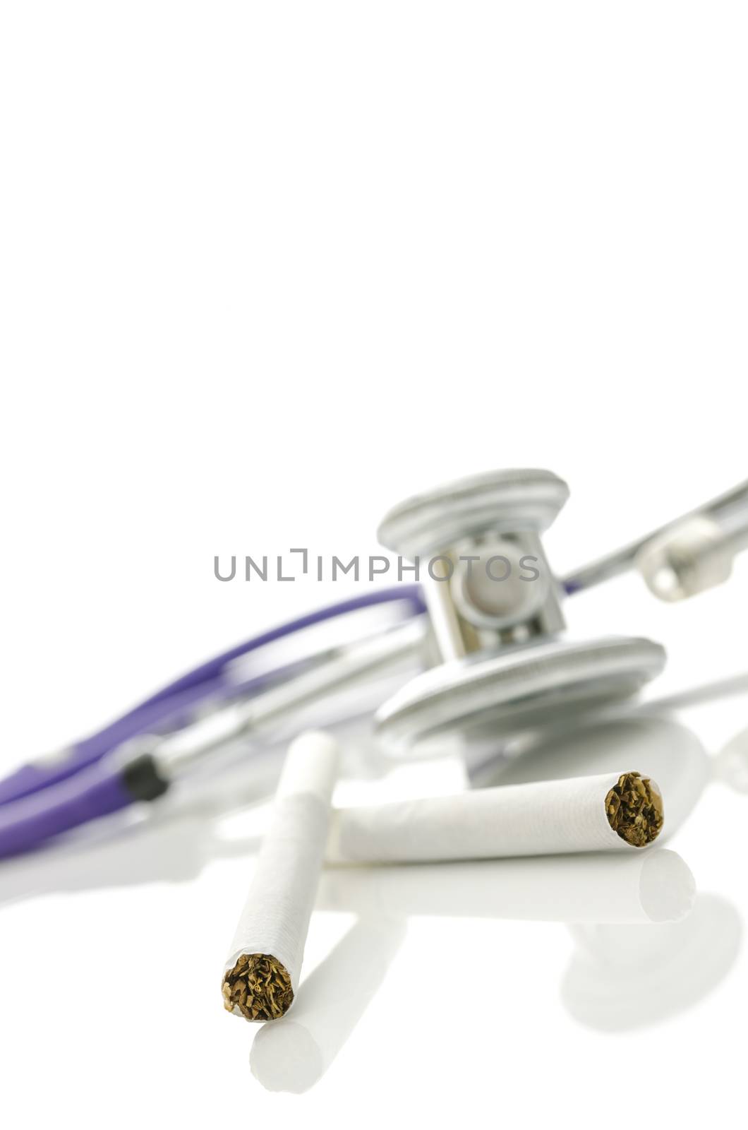 Cigarettes with stethoscope in background. Isolated over white background.