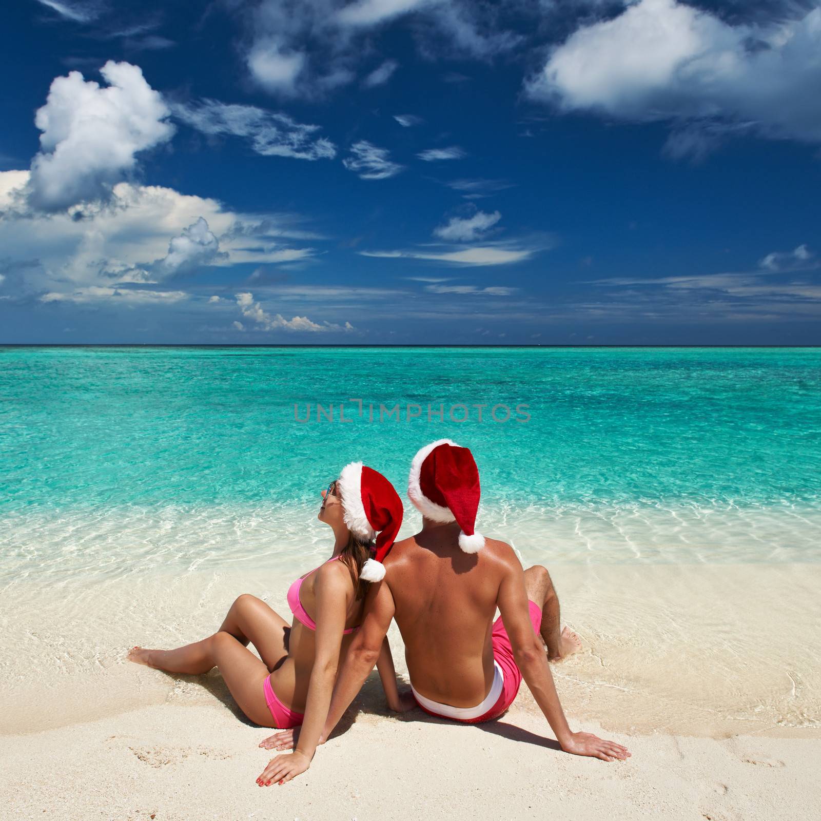 Couple in santa's hat on a tropical beach at Maldives