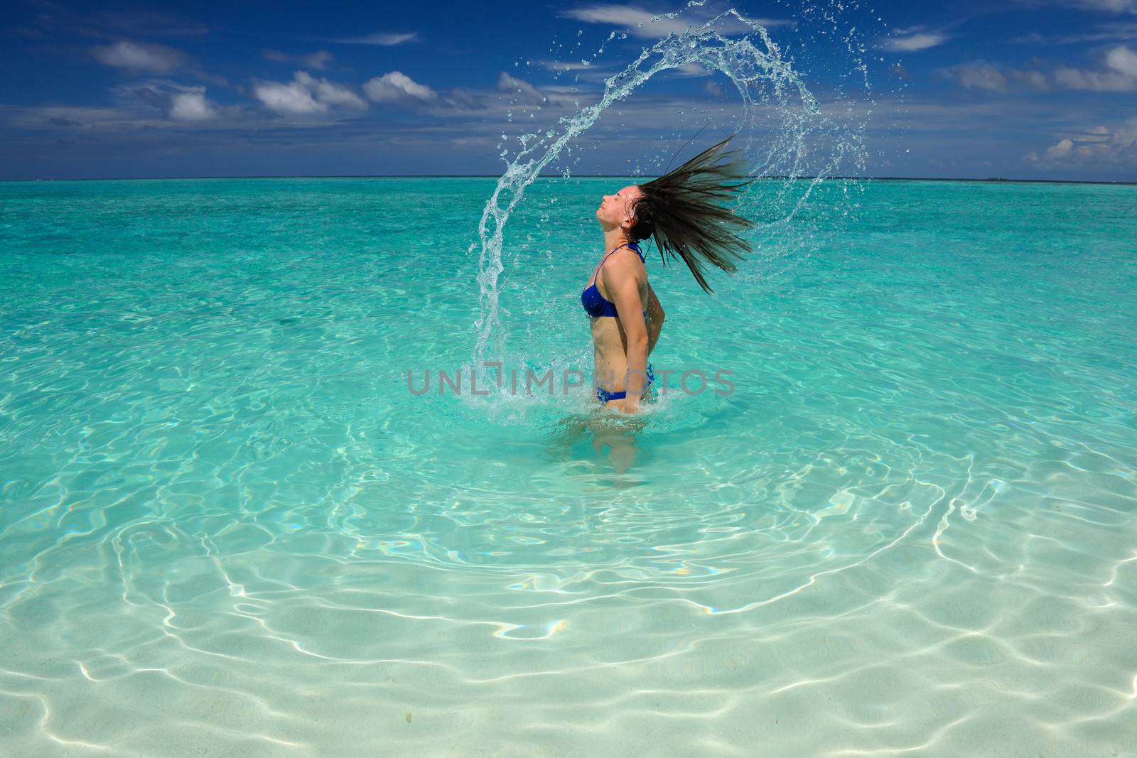 Woman splashing water with her hair in the ocean