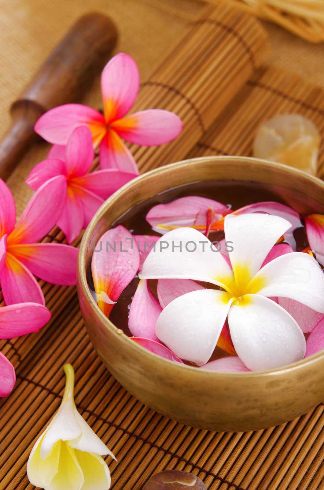 Spa setting, low light with ambient. Frangipani, hot and cold stone on bamboo mat.