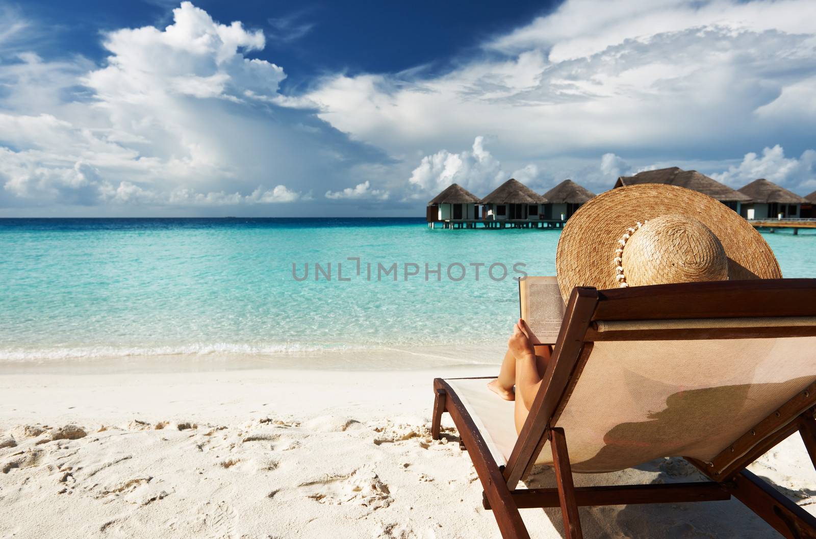 Young woman reading a book at beach by haveseen