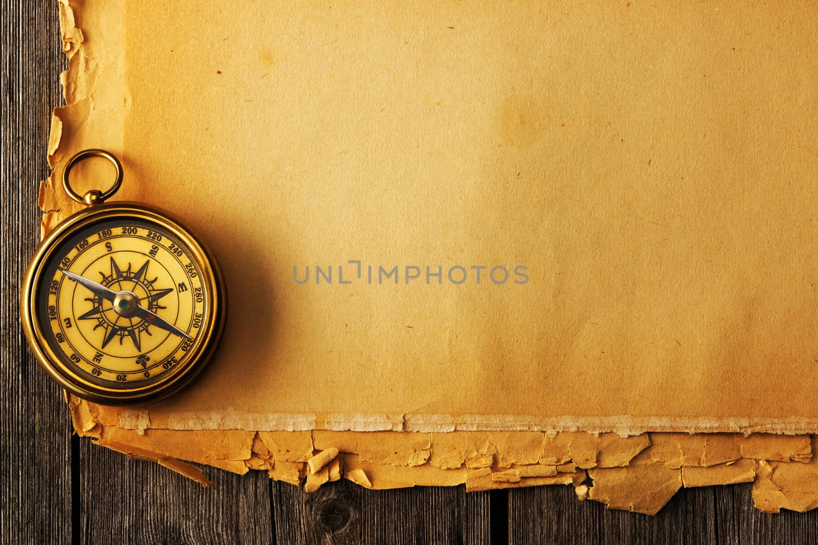 Antique brass compass over old paper background