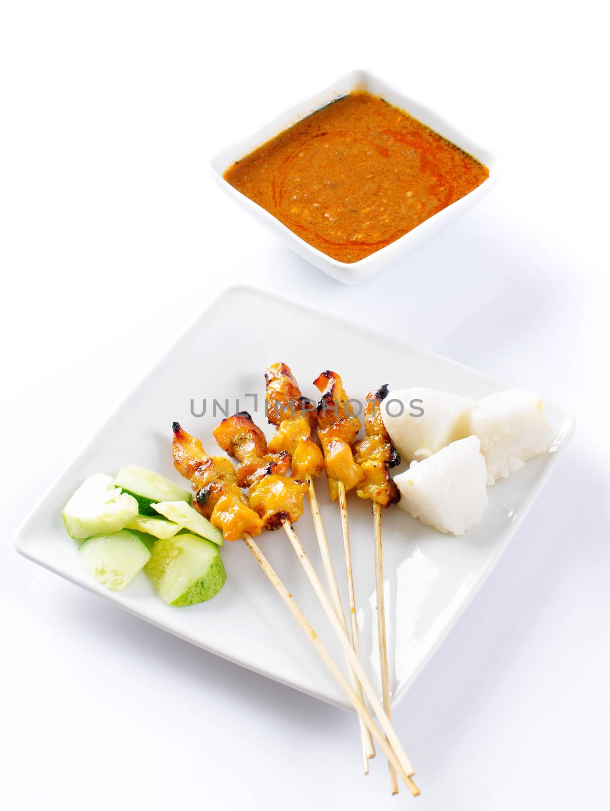 Chicken satay or sate, skewered and grilled meat, served with peanut sauce, cucumber and ketupat. Traditional Malay food. Delicious hot and spicy Malaysian dish, Asian cuisine.