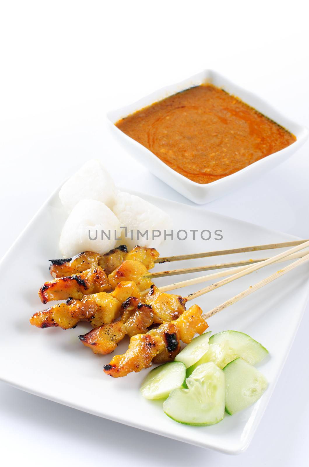 Chicken satay, skewered and grilled meat, served with peanut sauce, cucumber and ketupat. Traditional Malay food. Delicious hot and spicy Malaysian dish, Asian cuisine.