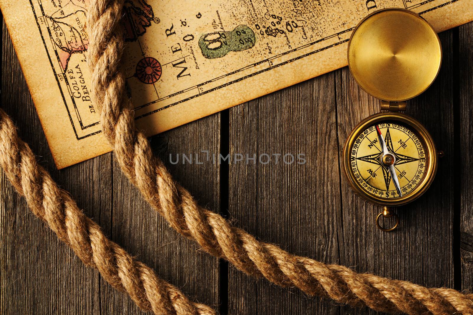 Antique brass compass and rope over old map