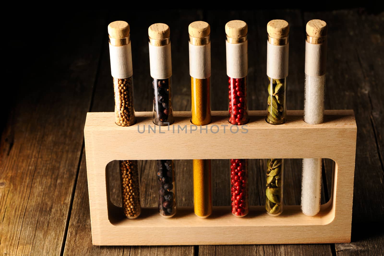 Spices in beakers on wooden table against dark background