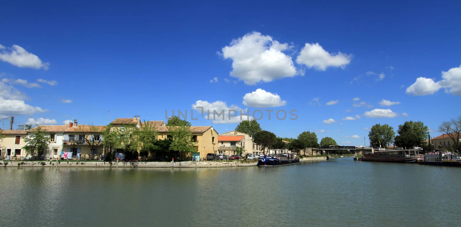 Canal with boats and houses by beautiful weather at Aigues-Mortes, Camargue, France