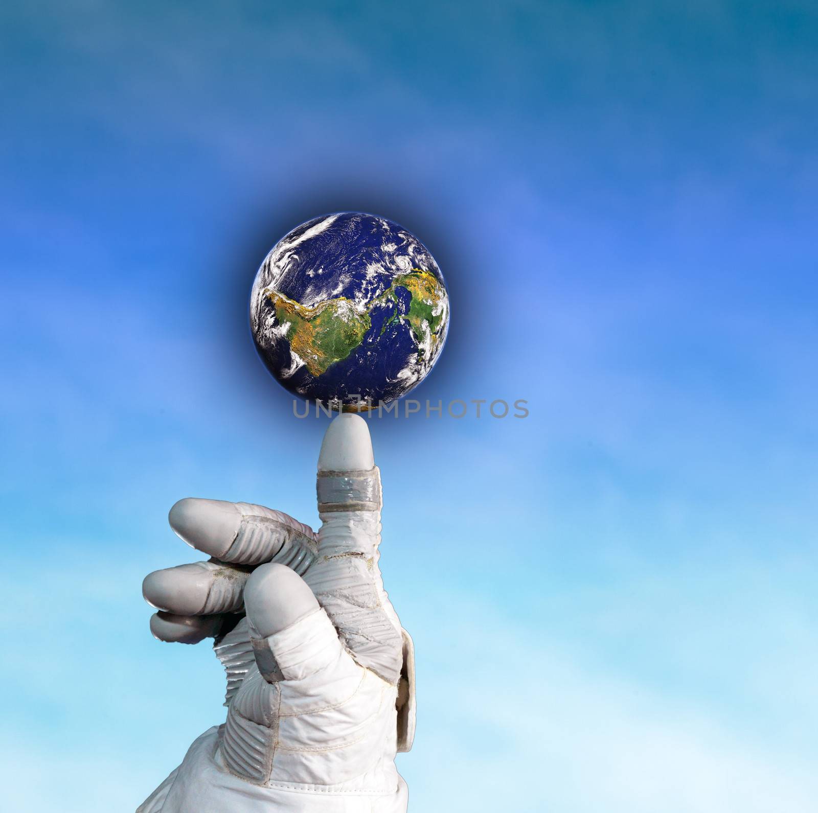 Hand of an astronaut holding the globe on his finger on blue sky background.
NASA Public Image Edited.