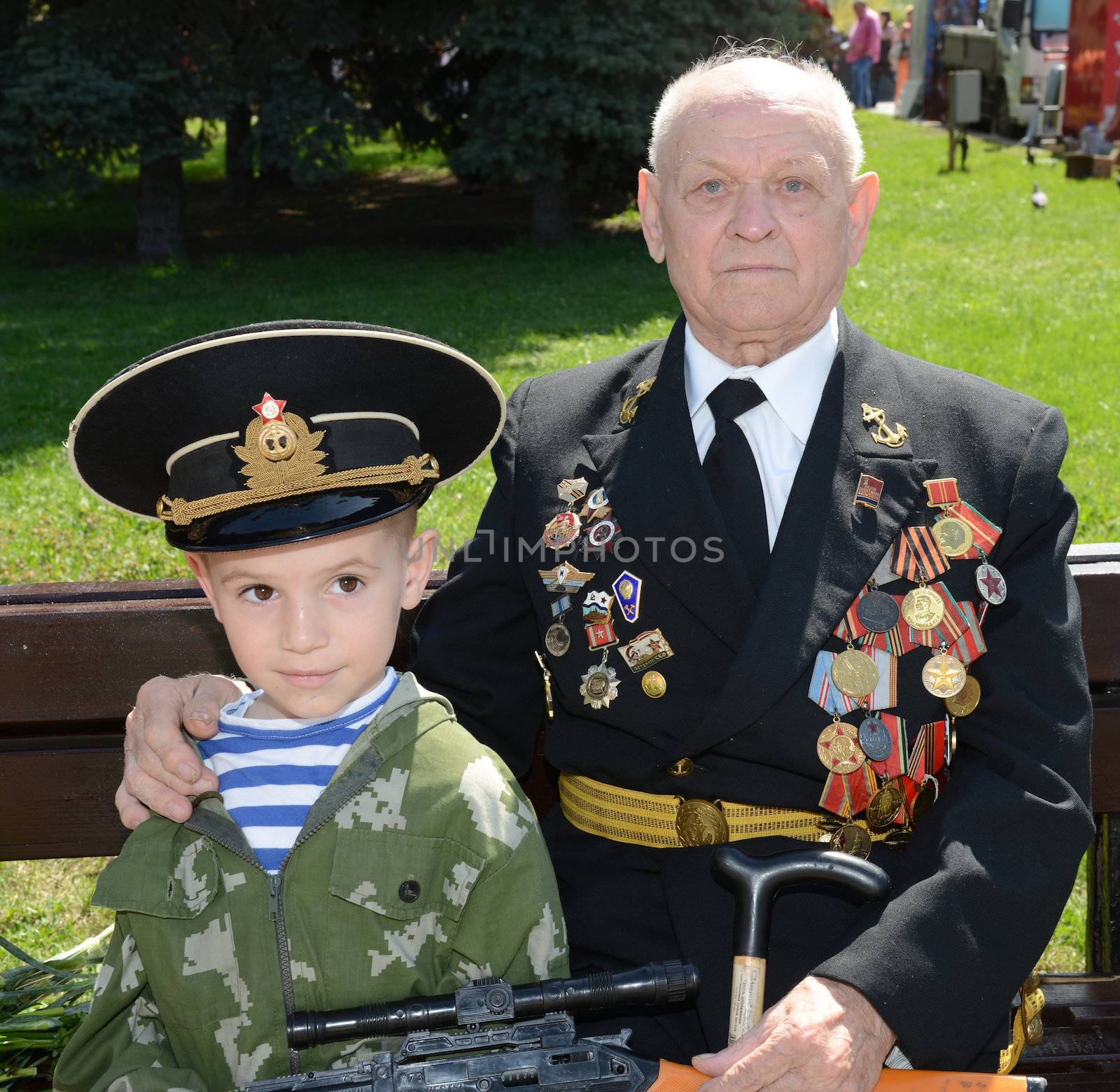 Moscow, Russia - May 9, 2013: Old man veteran of WWII in uniform decorated with numerous orders and medals and his grandson during festivities devoted to 68th anniversary of Victory Day.