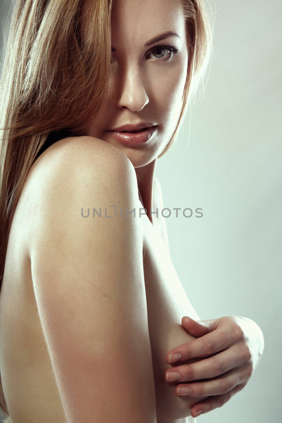 Beautiful blond lady embracing her naked breast. Studio shot