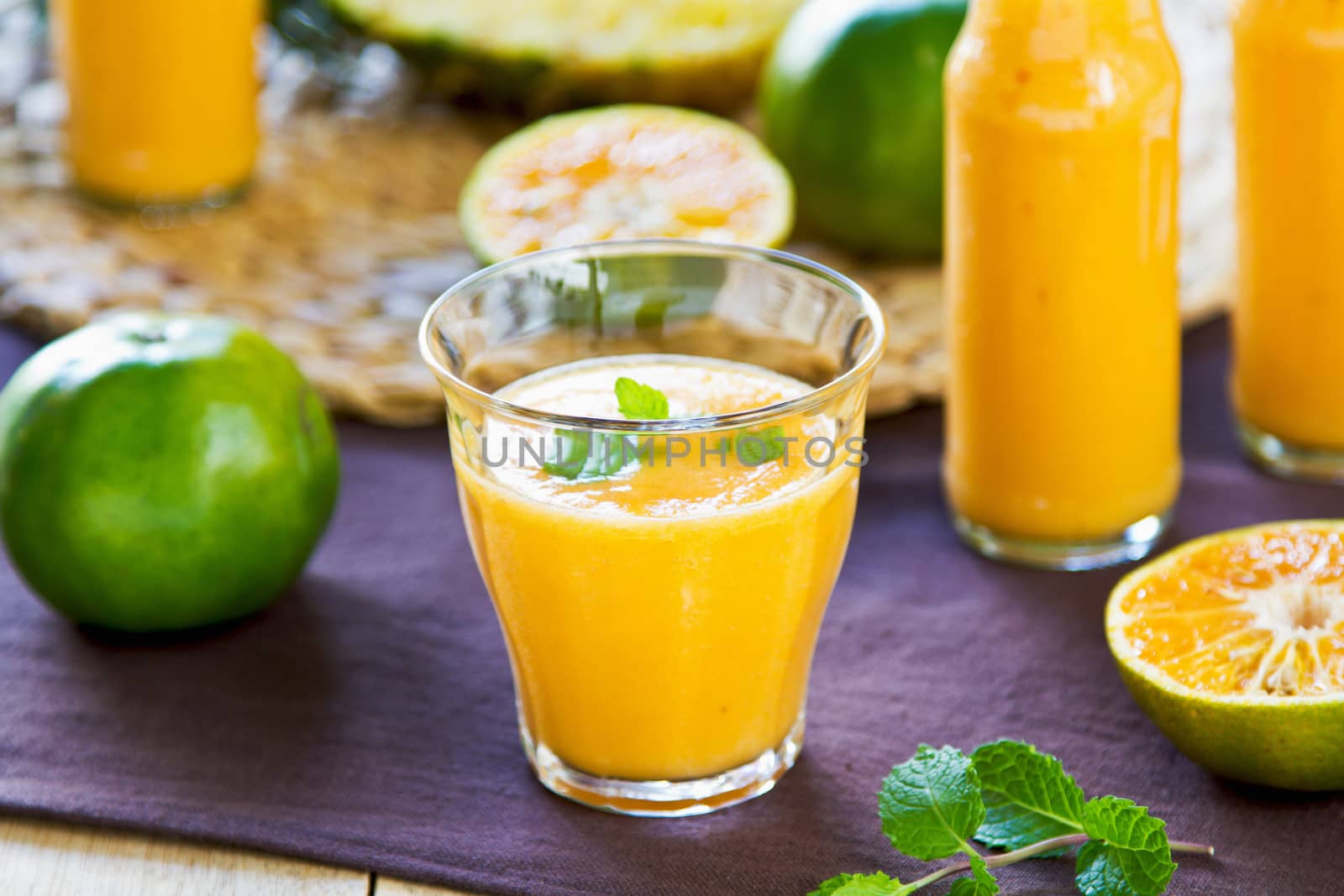 Pineapple with Orange and Mango smoothie in a glass and bottles