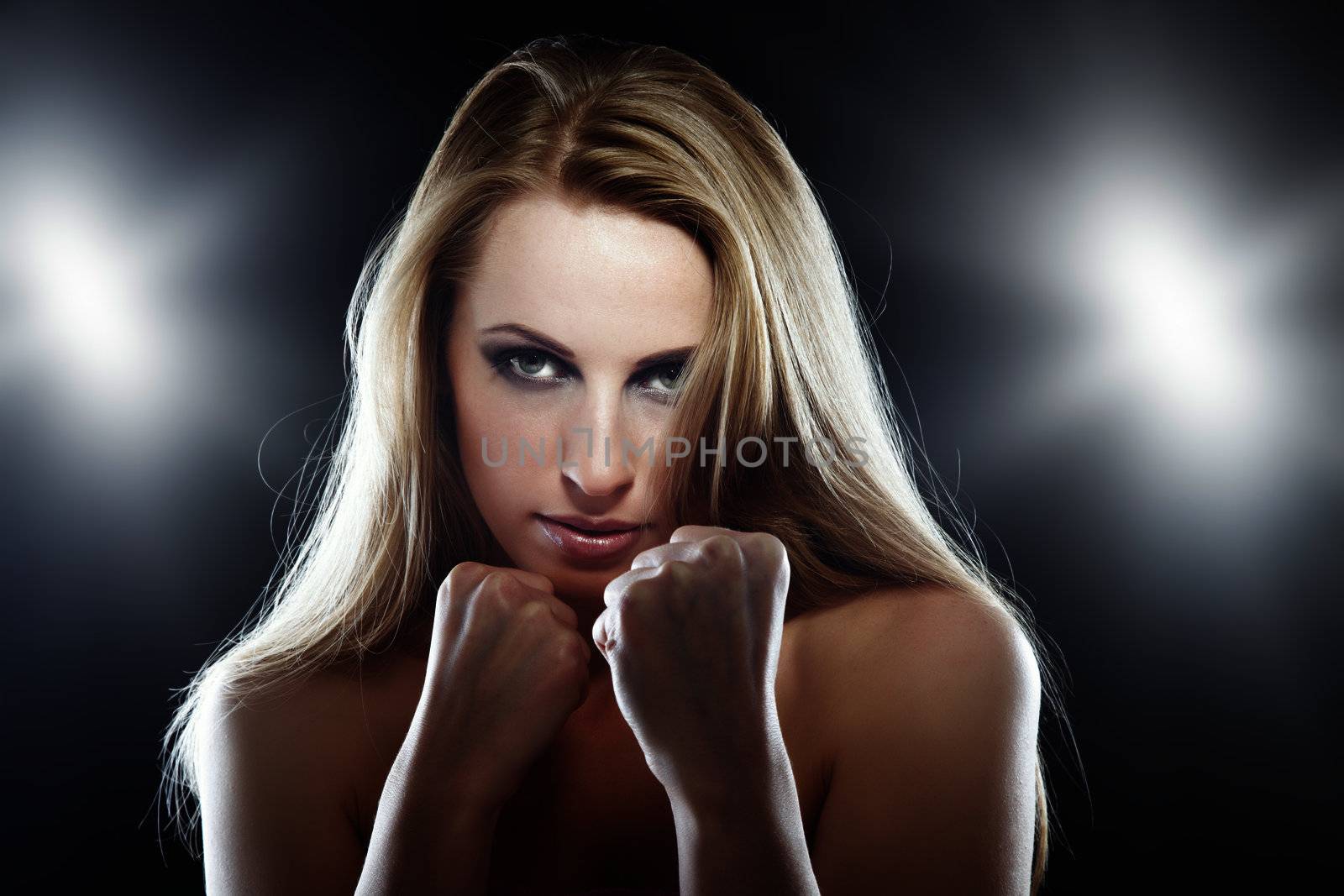 Horizontal photo of the blond female fighter in the studio with flash backlight