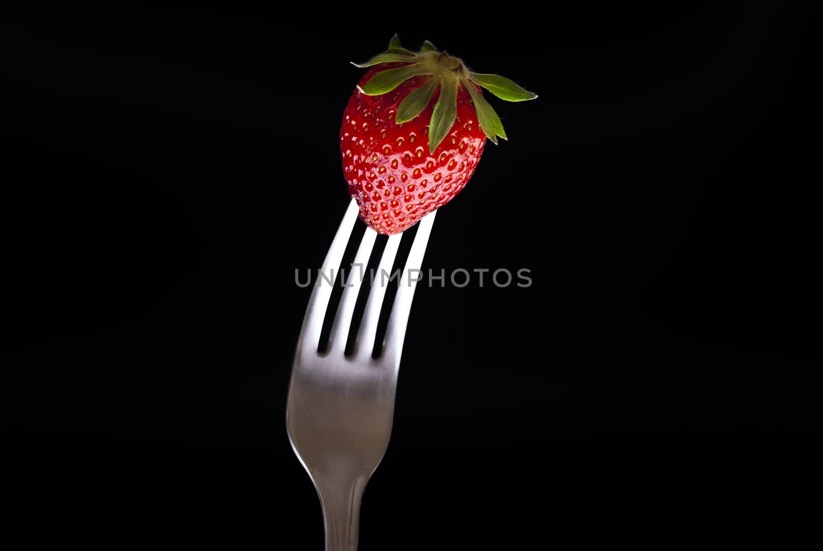 fresh strawberry on fork isolated on black background