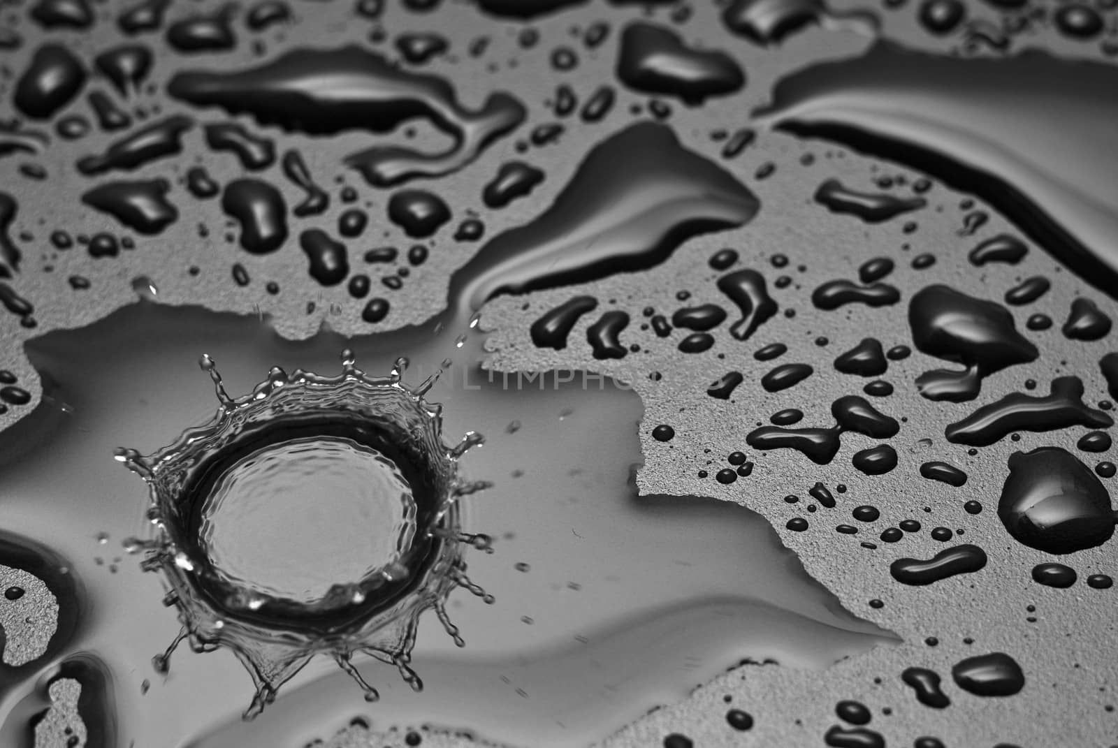A water drop forms a crown as it splashes into a pool of water.