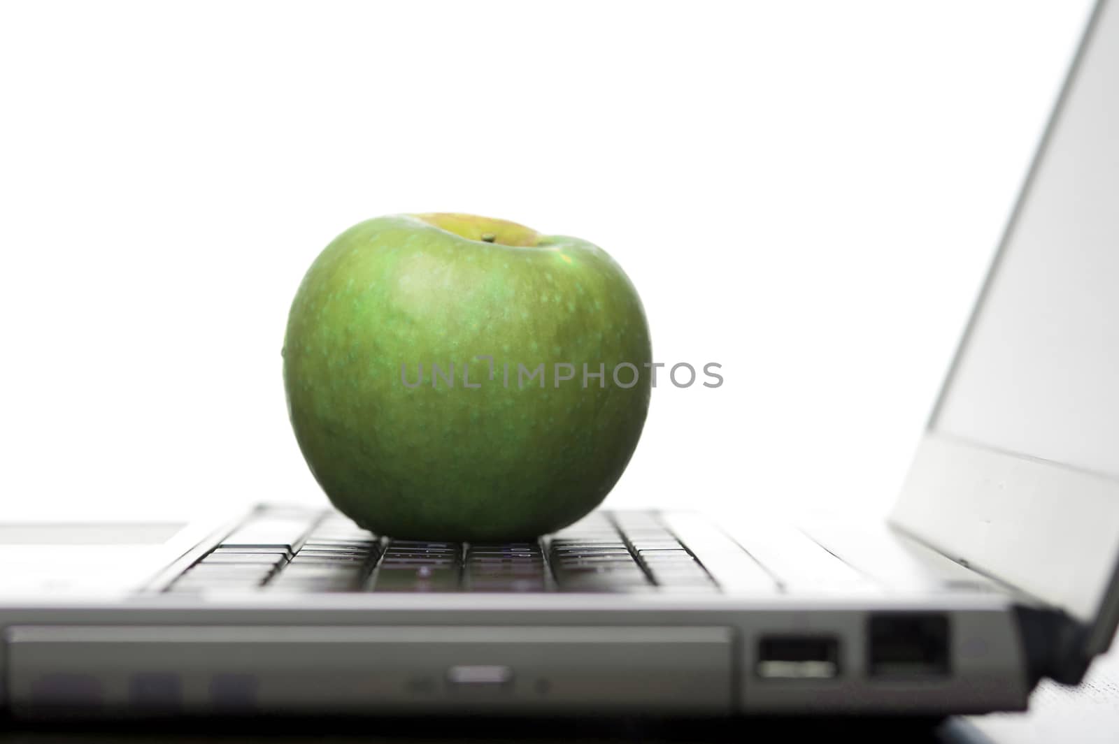 Green apple on an open laptop computer by stockarch