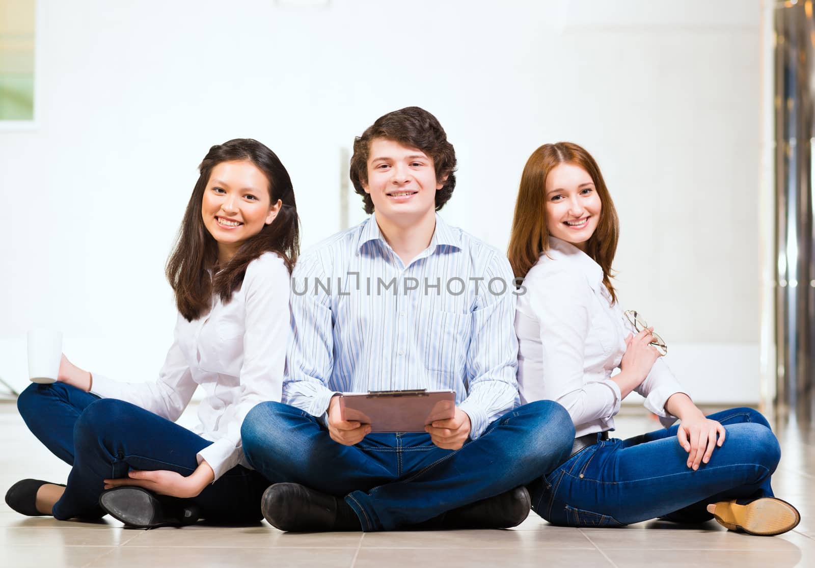 portrait of a group of young people sitting on the floor, man and two attractive women