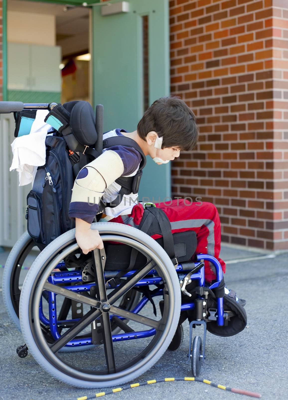 Disabled kindergartener trying to manuever wheelchair on playground at recess