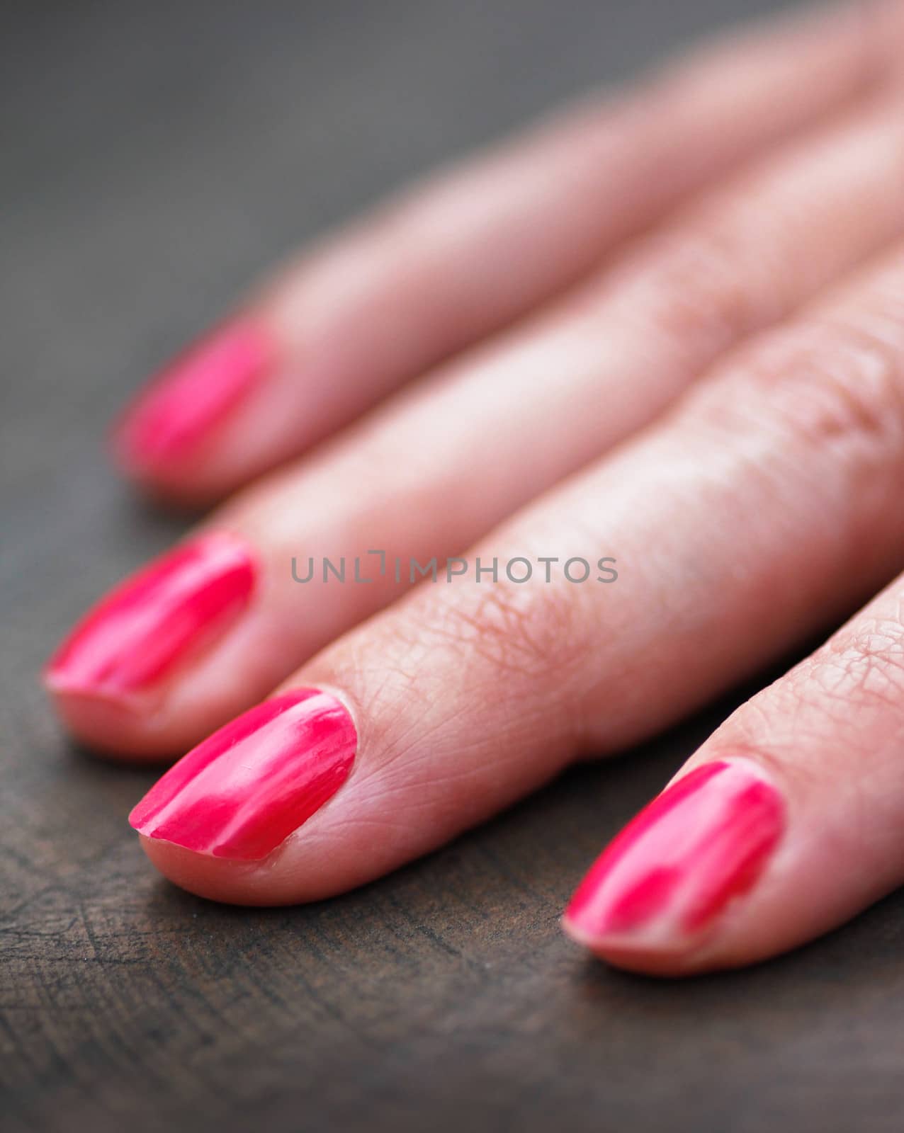 right hand fingers of a caucasian woman with a wooden background