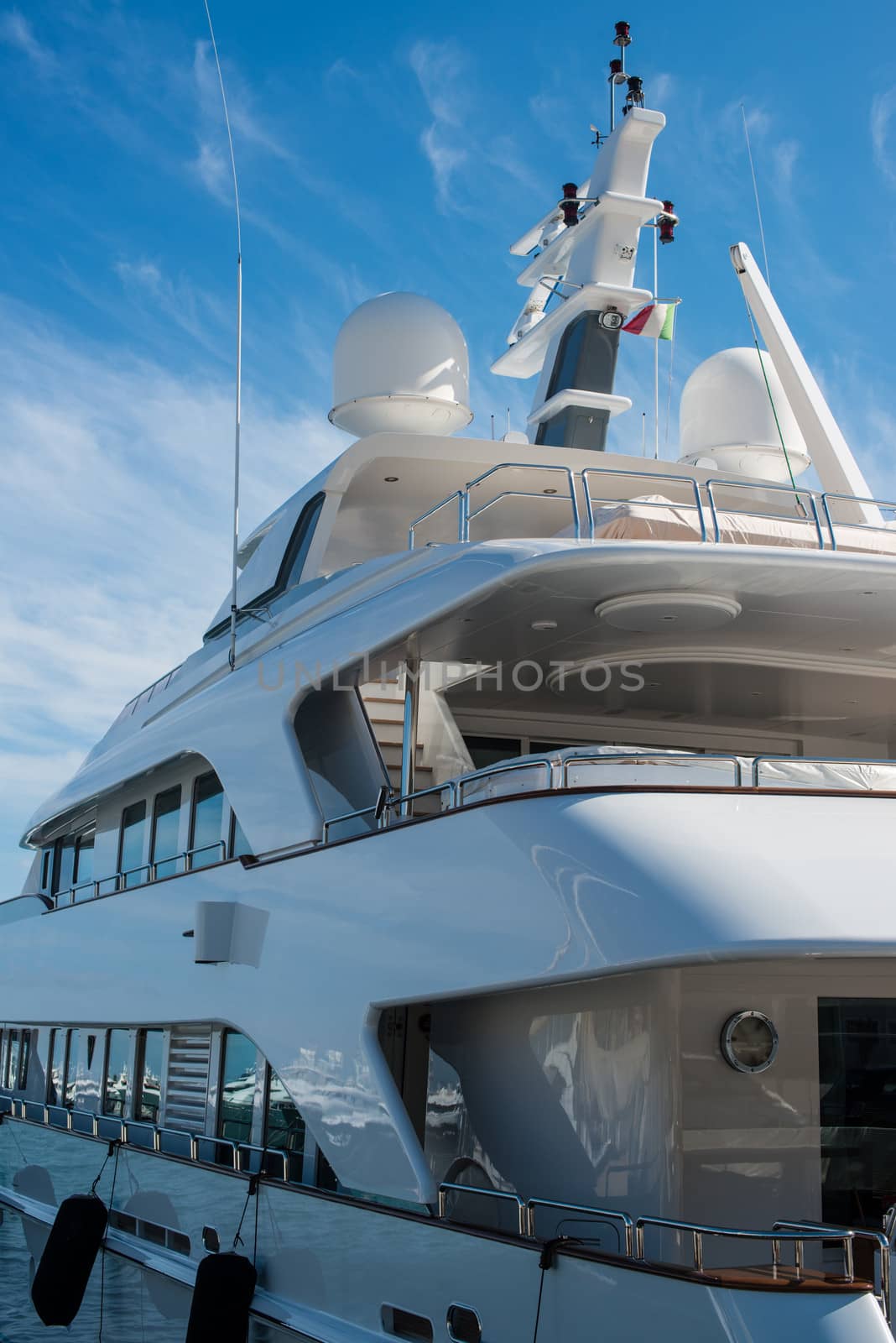 Luxury yacht with Italian flag docked in marina on a bright day