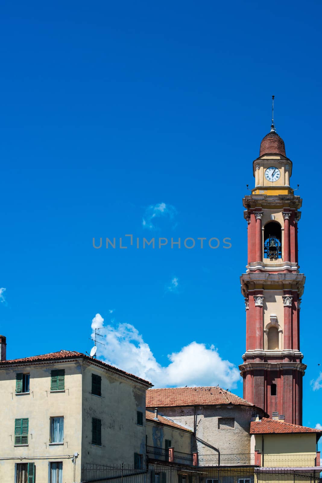 Church tower and buildings in Cairo Montenotte, Liguria (Italy) with great blue sky and room for your text