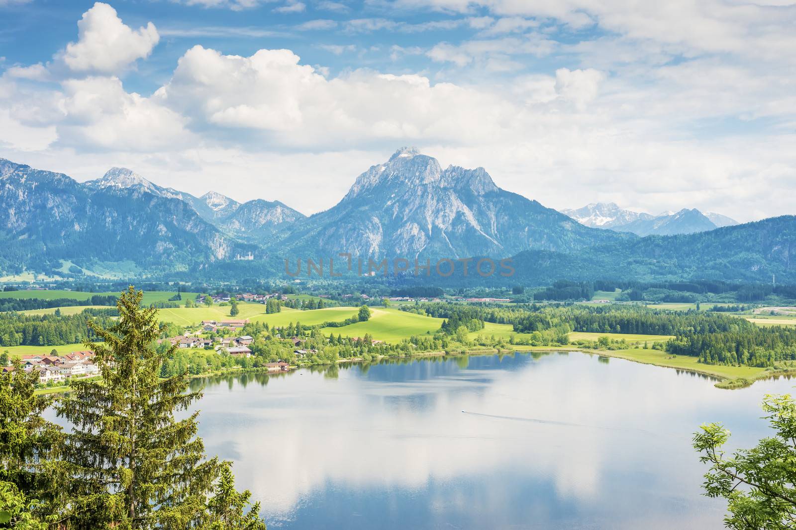 Lake named Hopfensee in Bavaria Germany with alps and blue sky with white clouds