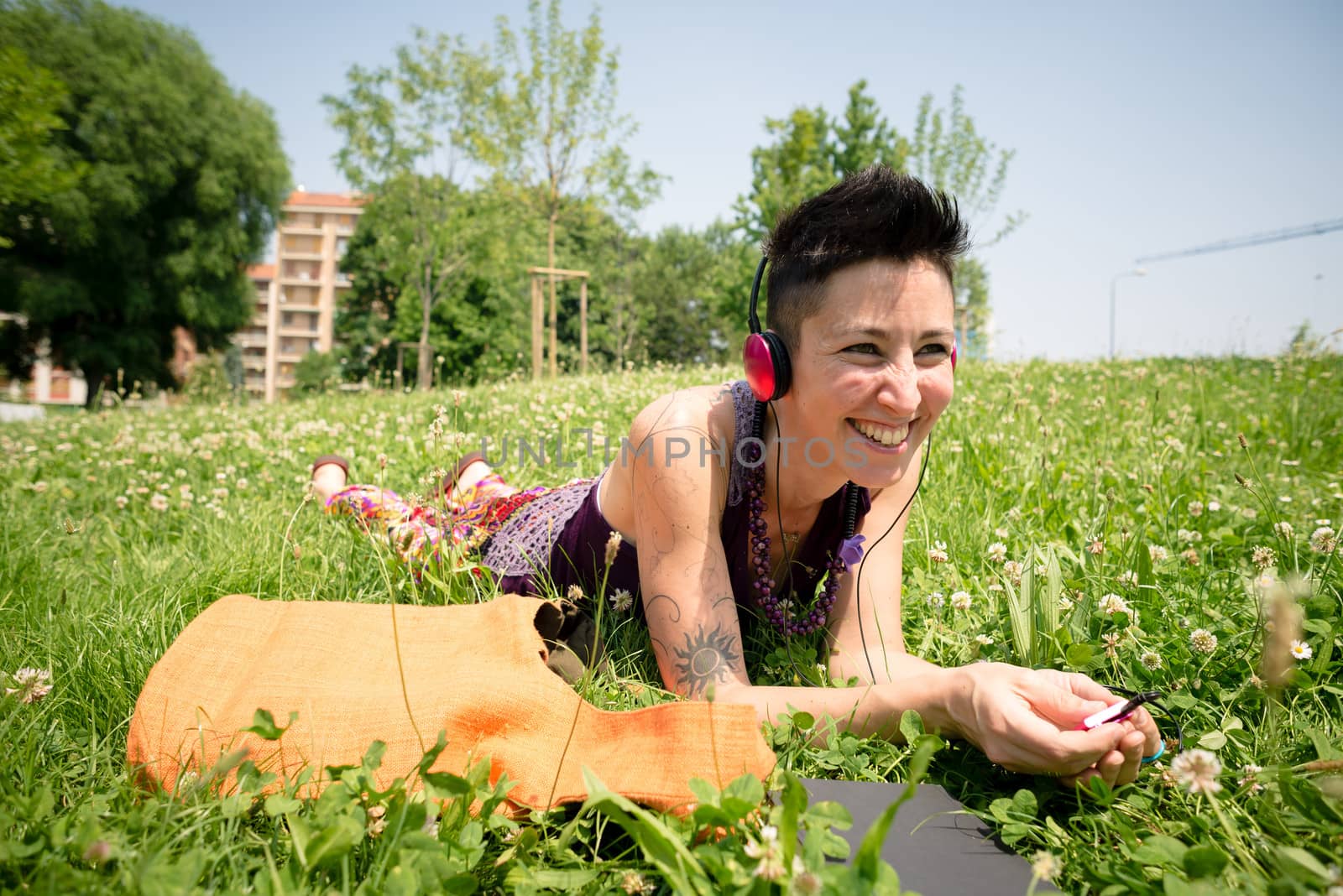 beautiful hipster short hair woman listening music in the park in the city