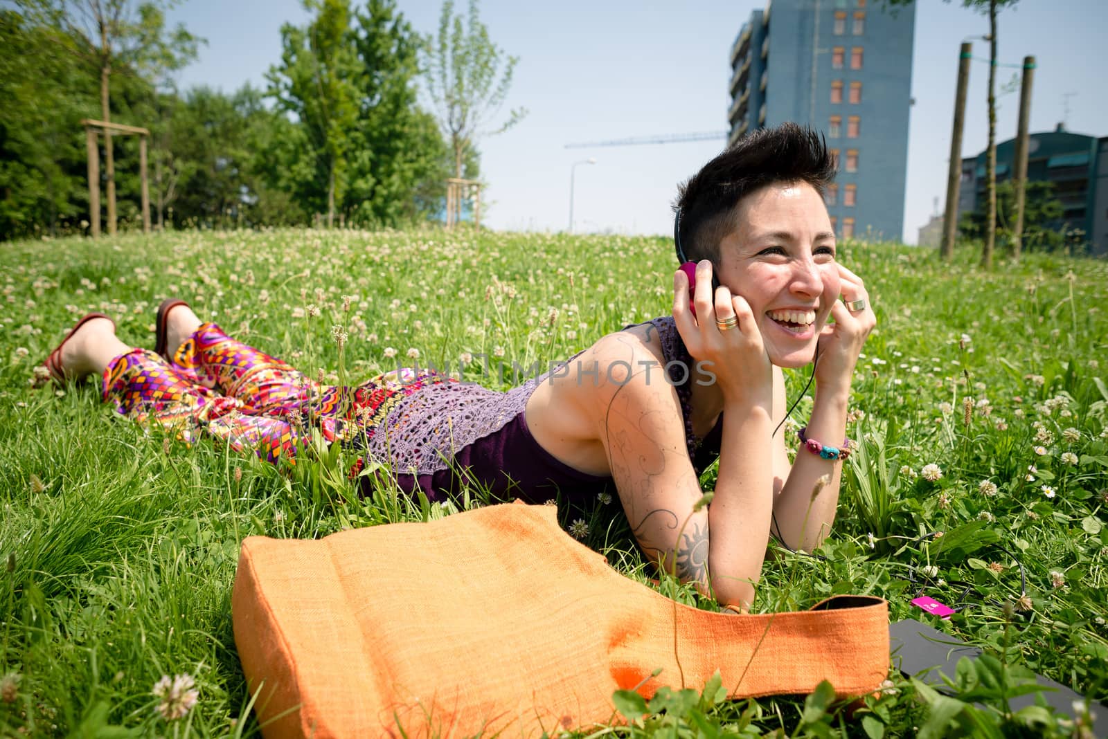 beautiful hipster short hair woman listening music in the park in the city