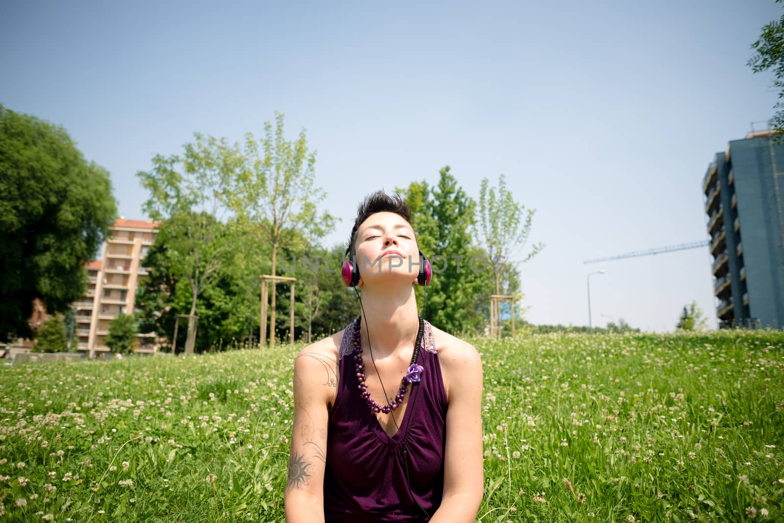beautiful hipster short hair woman listening music in the park in the city