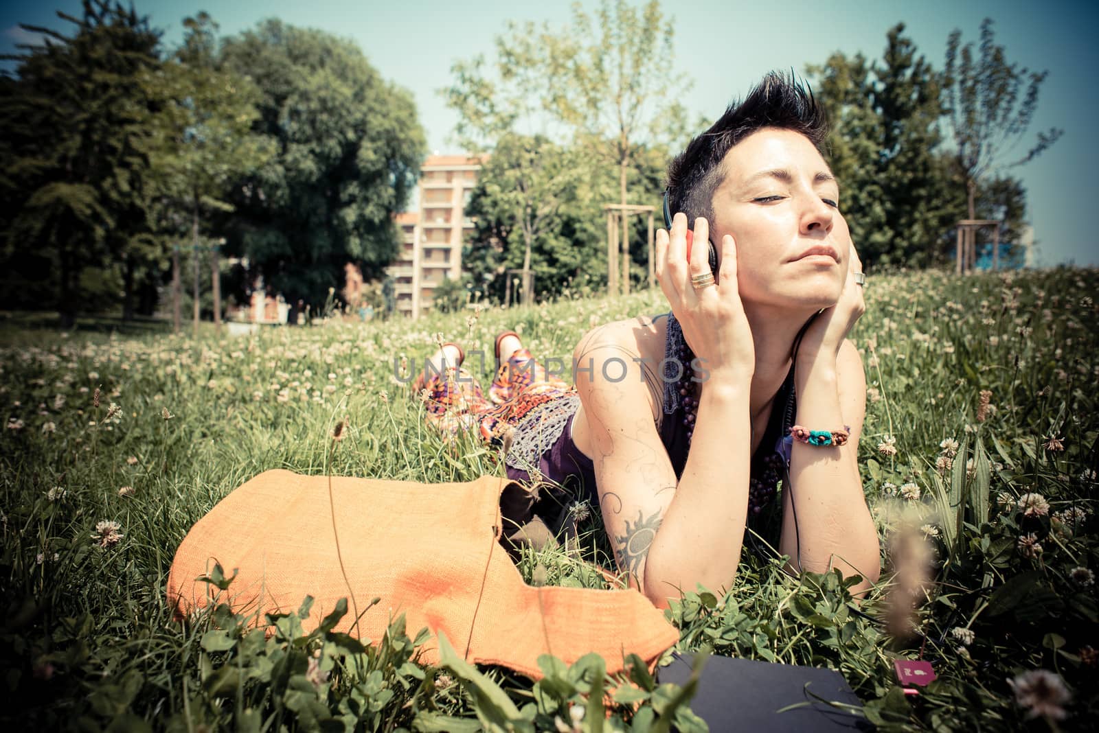 beautiful hipster short hair woman listening music in the park in the city