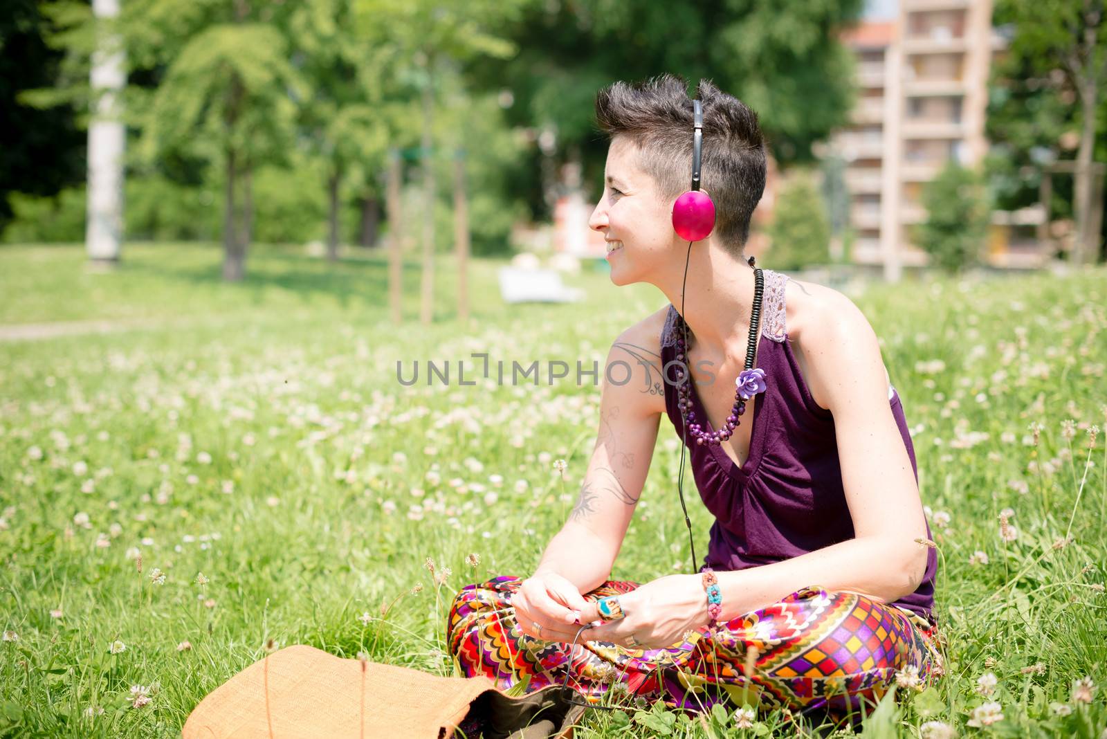 beautiful hipster short hair woman listening music in the park in the city