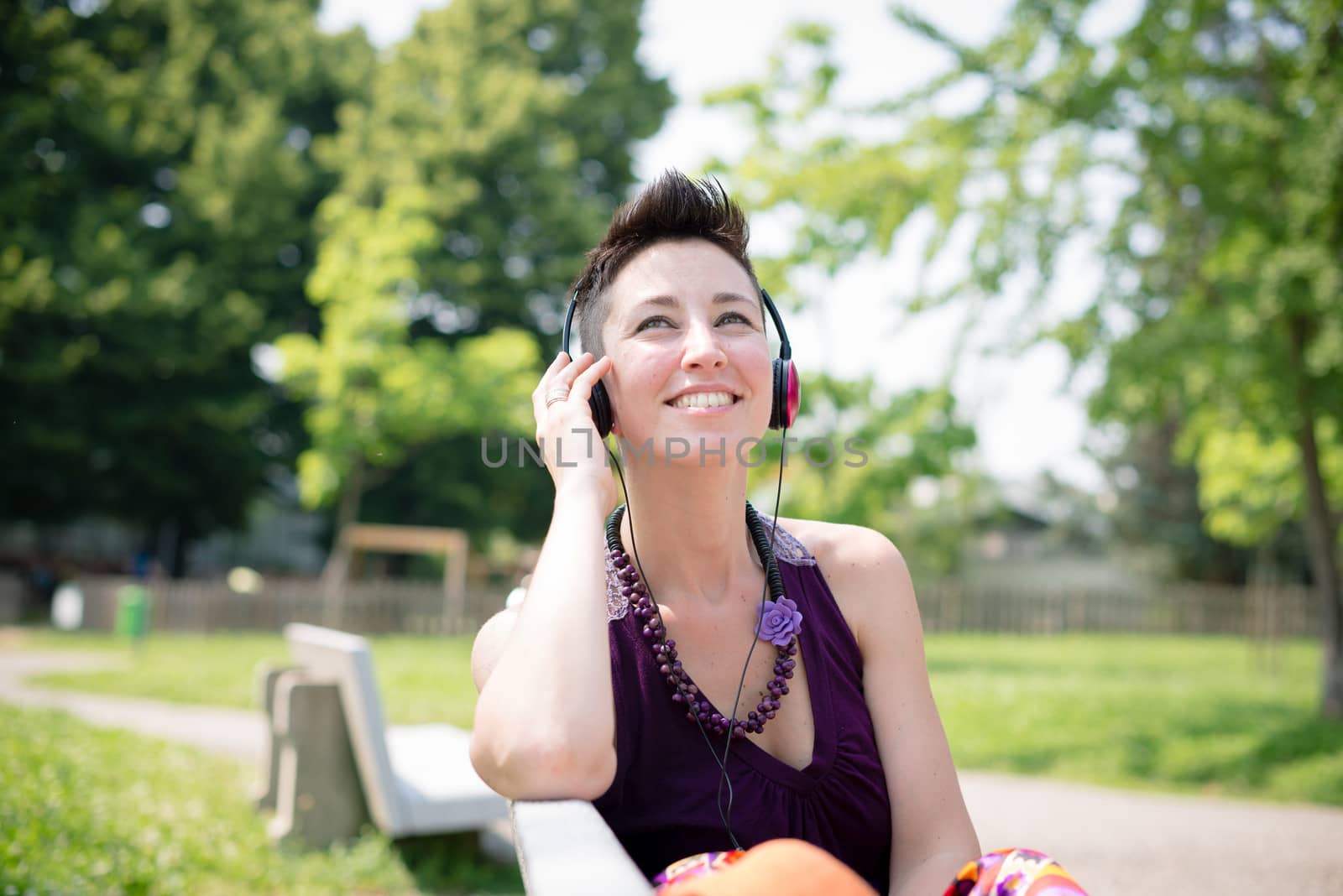beautiful hipster short hair woman listening music in the park in the city