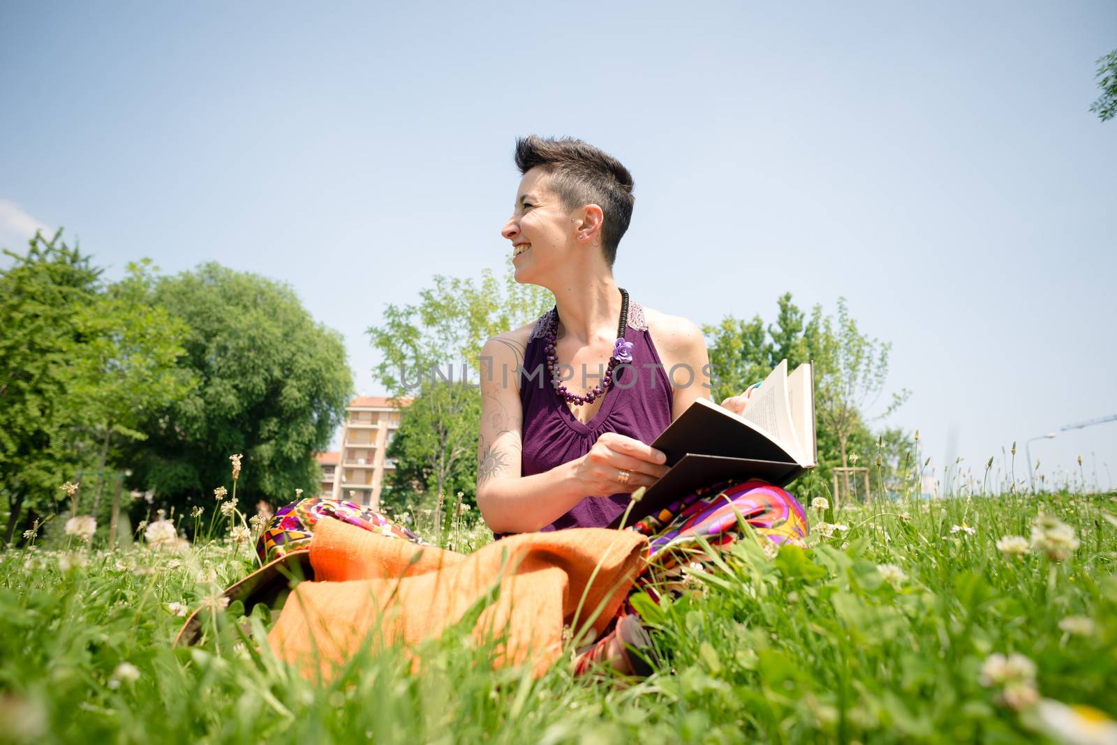 beautiful hipster short hair woman reading book in the park in the city