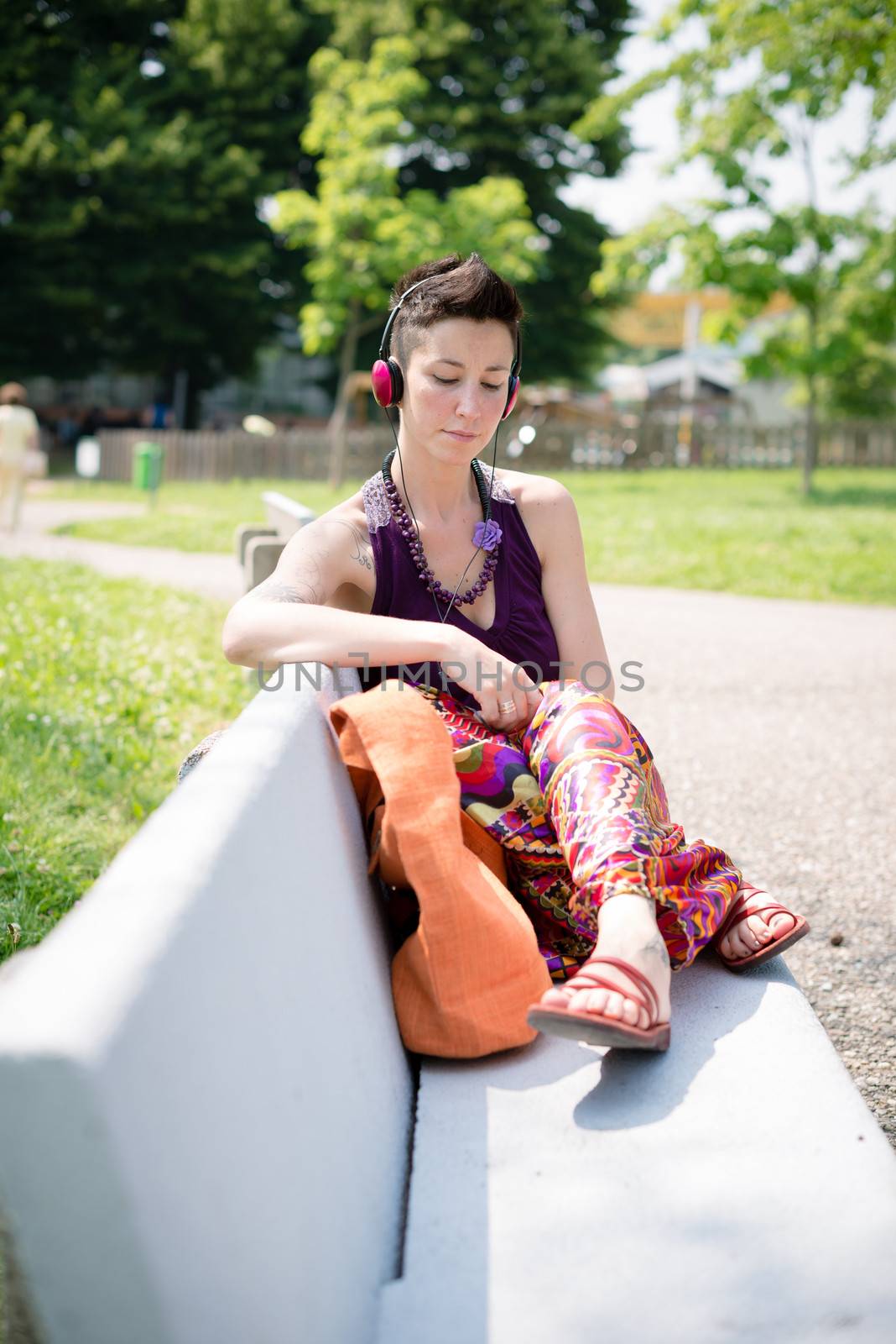 beautiful hipster short hair woman listening music in the park in the city