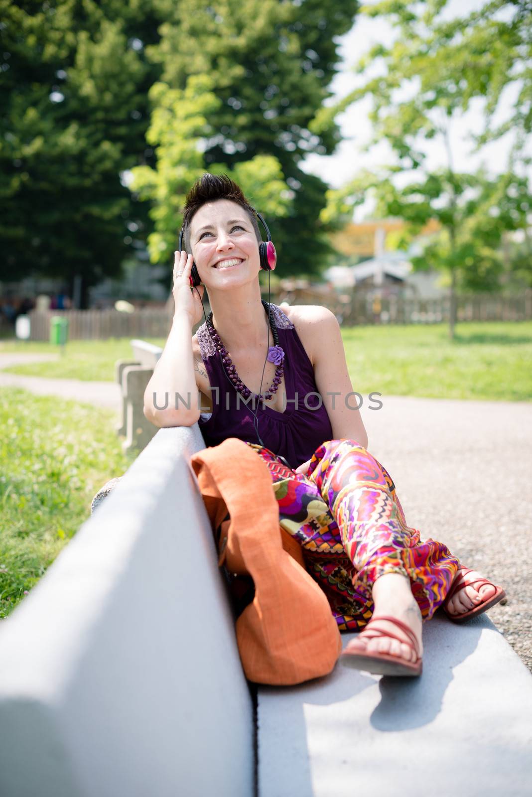 beautiful hipster short hair woman listening music in the park in the city