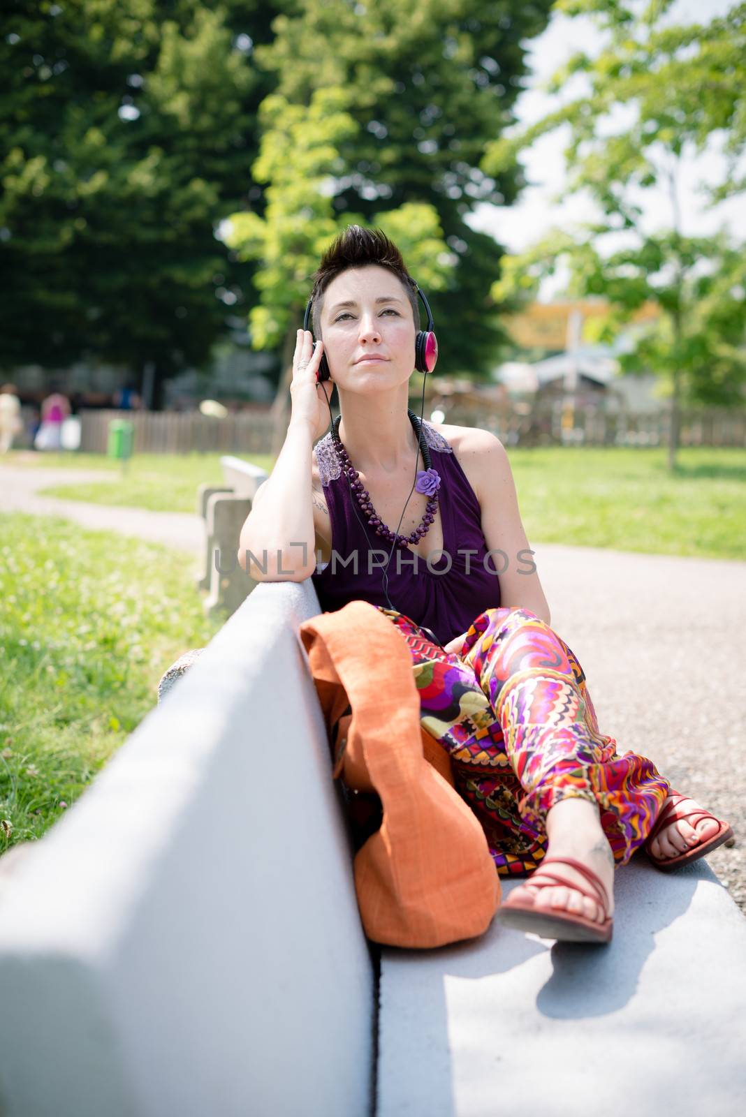 beautiful hipster short hair woman listening music in the park in the city