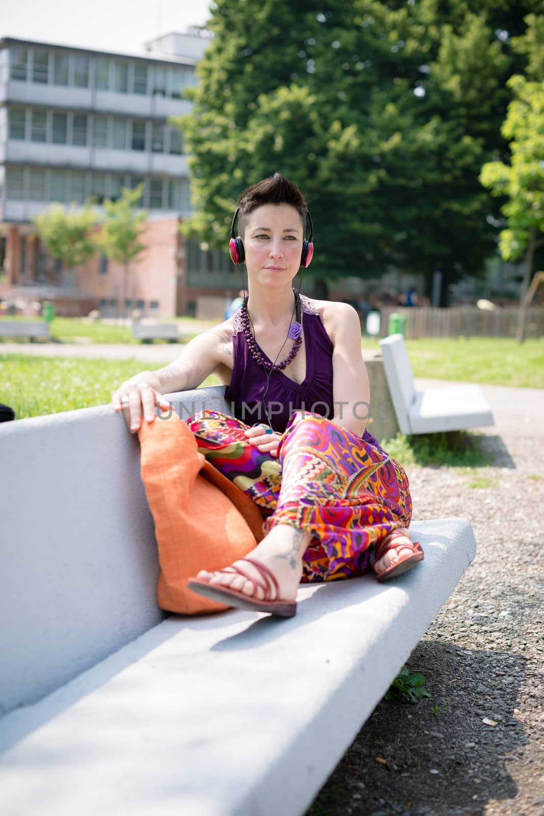 beautiful hipster short hair woman listening music in the park in the city