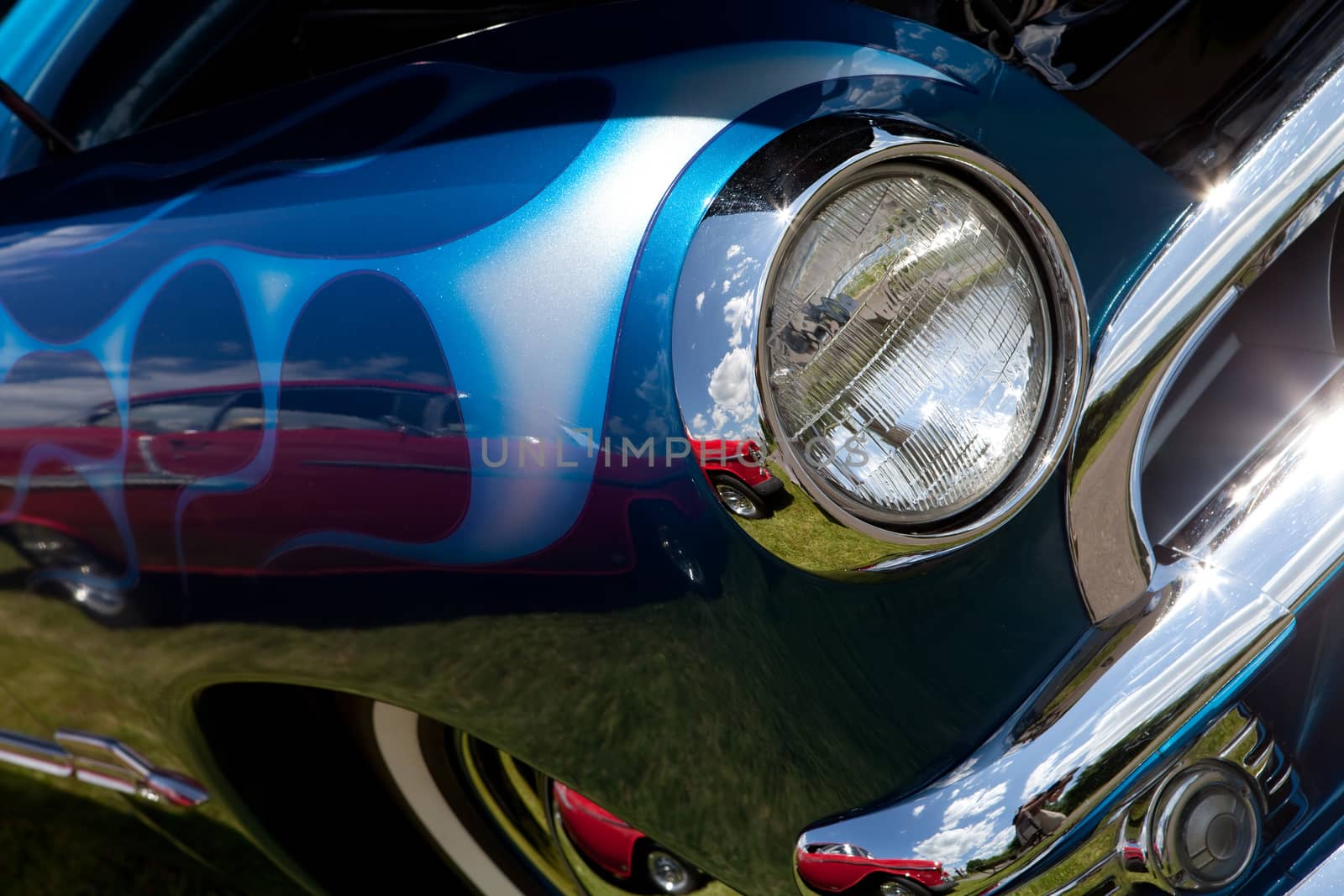 A closeup of the headlight and front bumper on a vintage car.