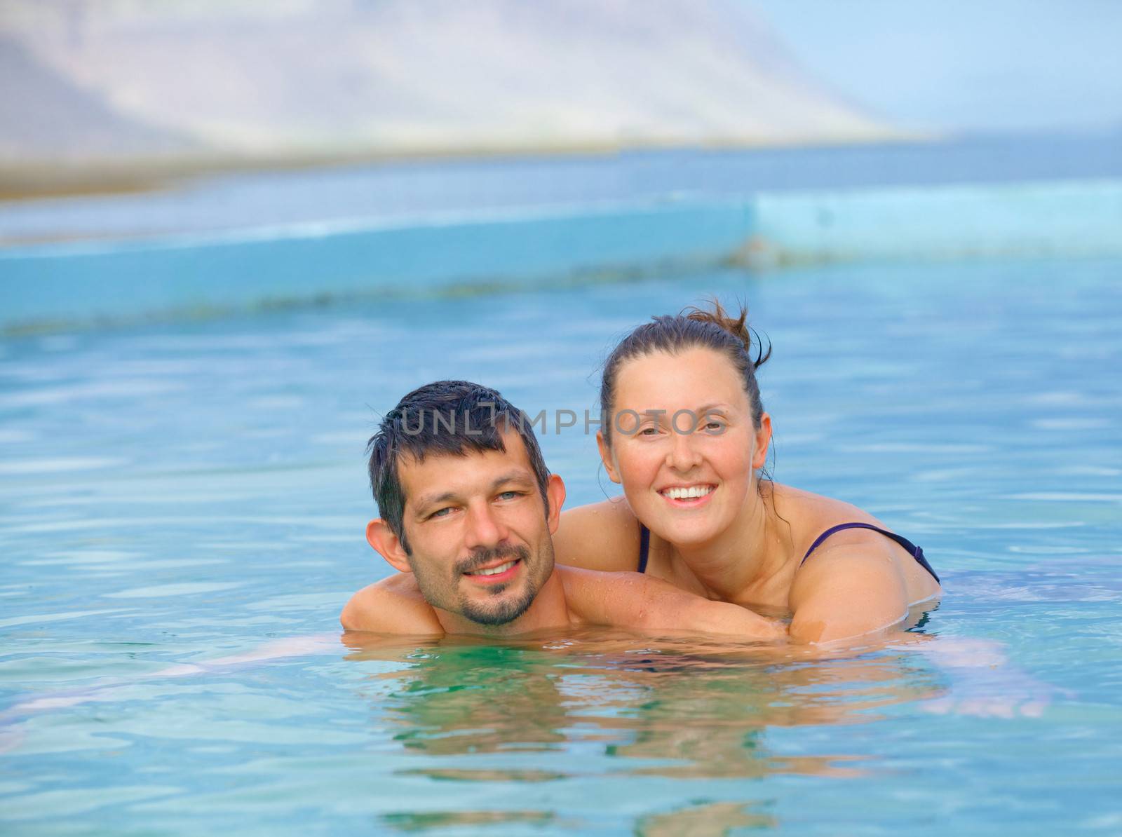 Smiling happy couple in geothermal mineral pool. Iceland