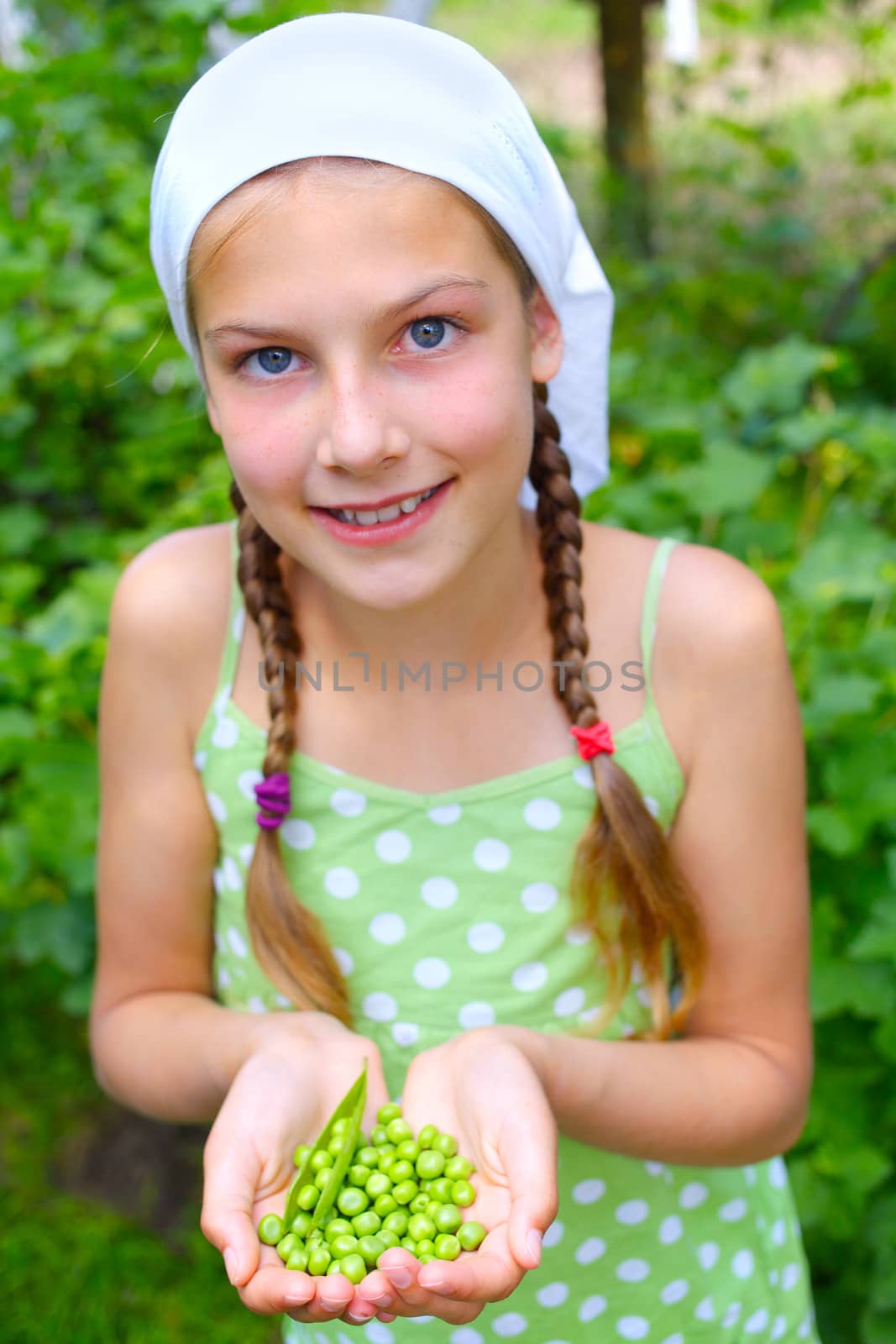 Portrait of beautiful girl holding green Peas in garden
