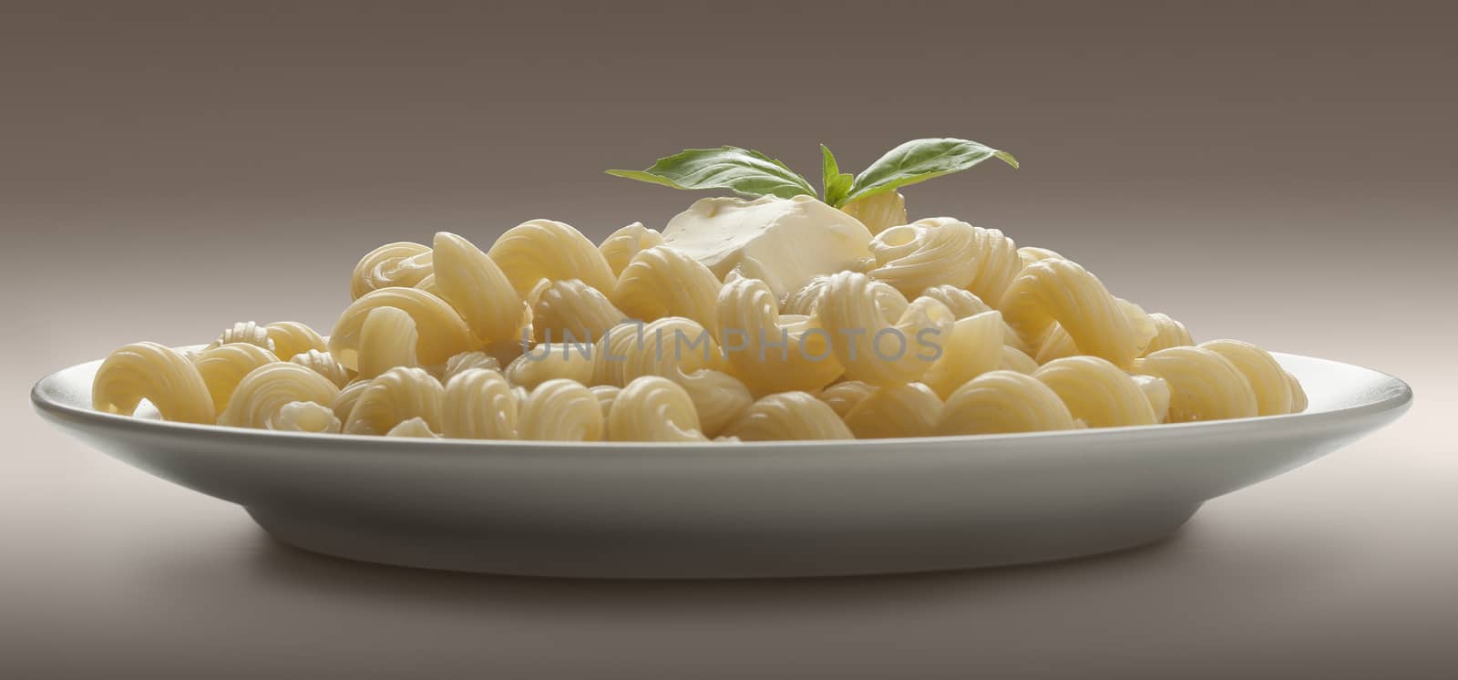 Some boiled pasta with butter and fresh green basil on the plate