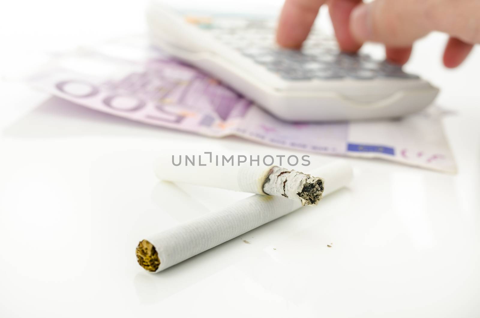 Half burned cigarette with male hand calculating costs of smoking addiction.